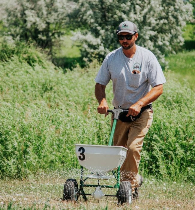 Warne Green Force worker fertilizing a landscape with professional products Warne Green Force worker fertilizing a landscape with professional products